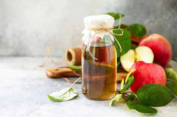 Apple vinegar. Healthy organic food. A bottle of apple cider vinegar on a light stone countertop. Copy space.